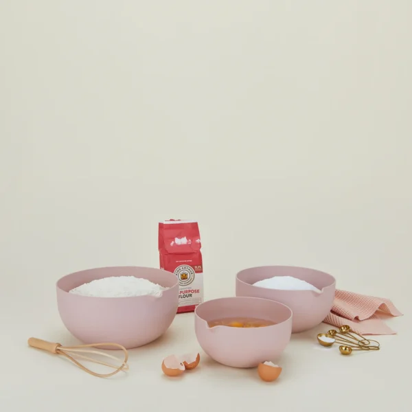 Essential Mixing Bowls Blush with flour, eggs and kitchen towel on the side.
